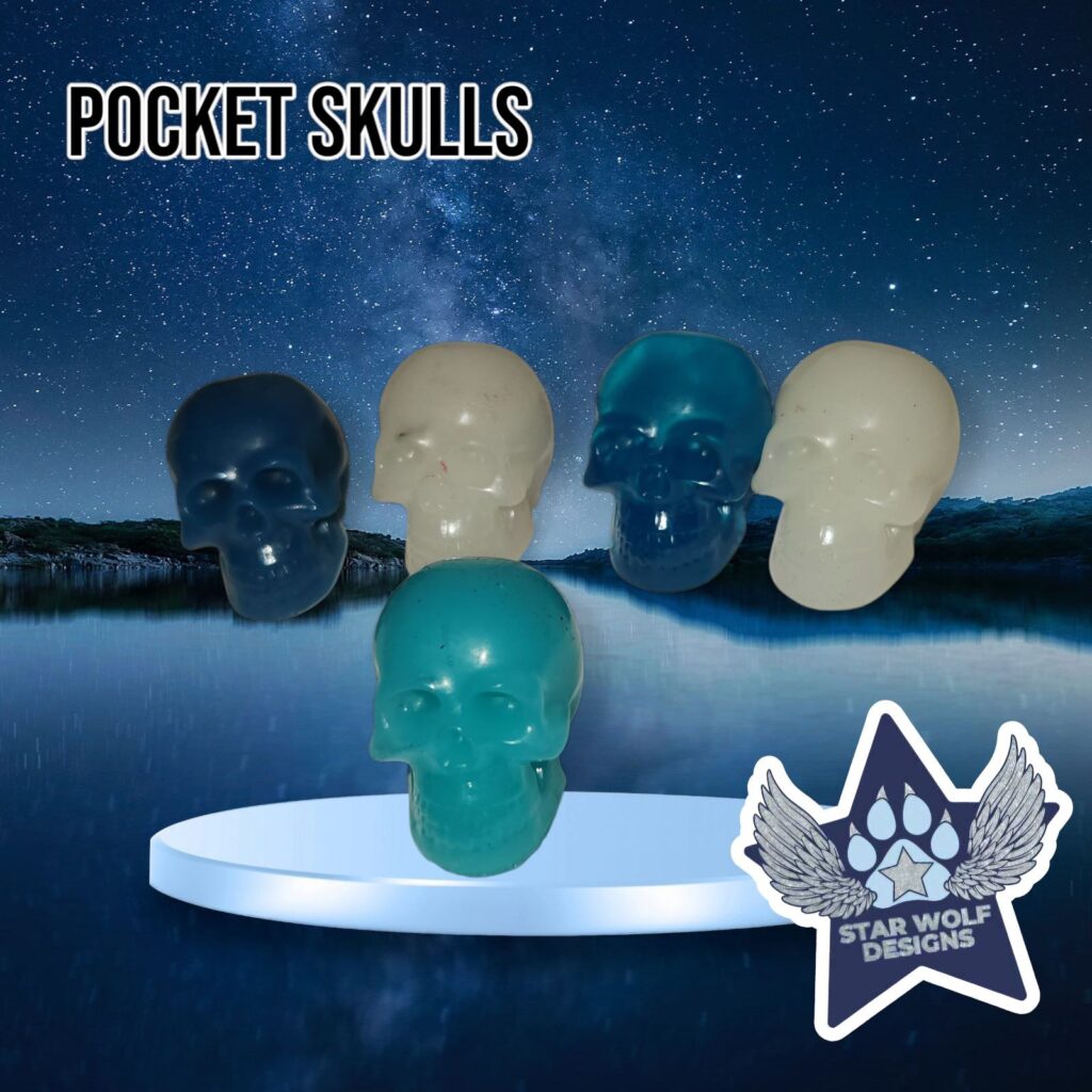 Four small resin Pocket Skulls in white, blue, and teal