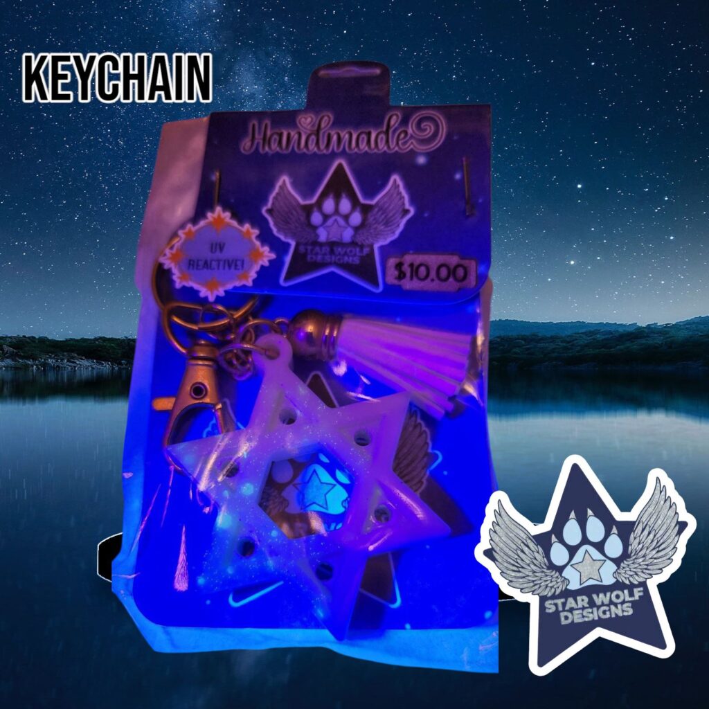Keychain glowing under UV light on a Star Wolf Designs card