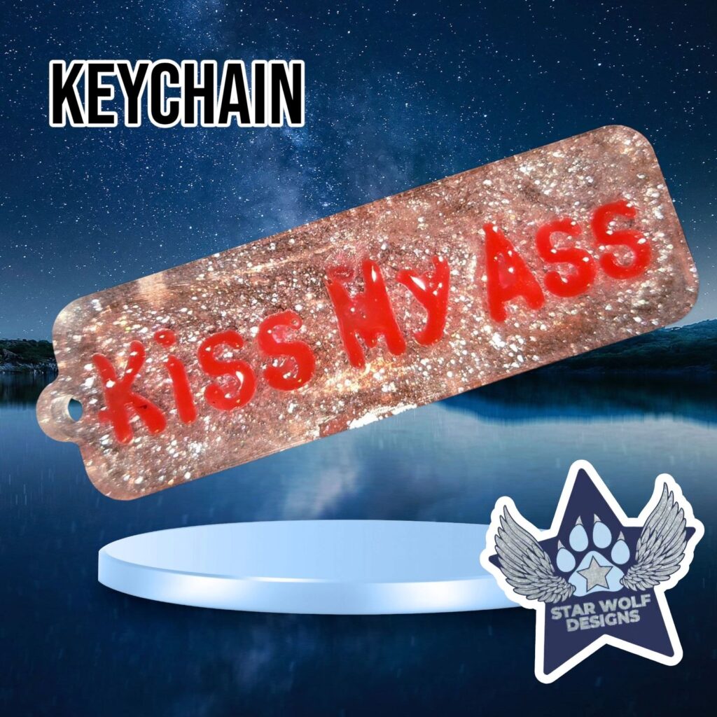 Pink glitter keychain reading “Kiss My Ass”